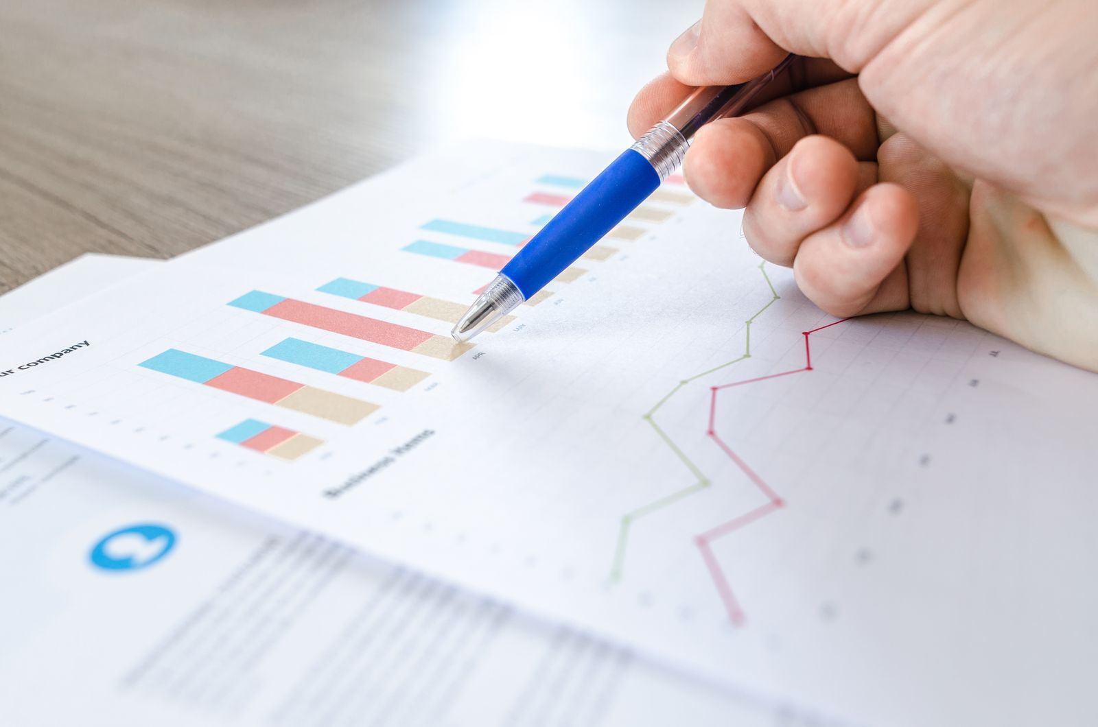 Hand pointing a pen at printed charts